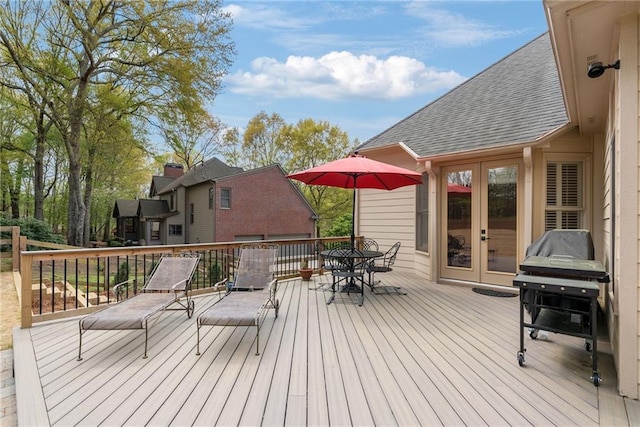 wooden deck with french doors, outdoor dining space, and a grill