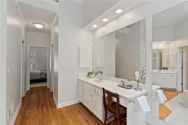 ensuite bathroom featuring crown molding, wood finished floors, visible vents, and vanity