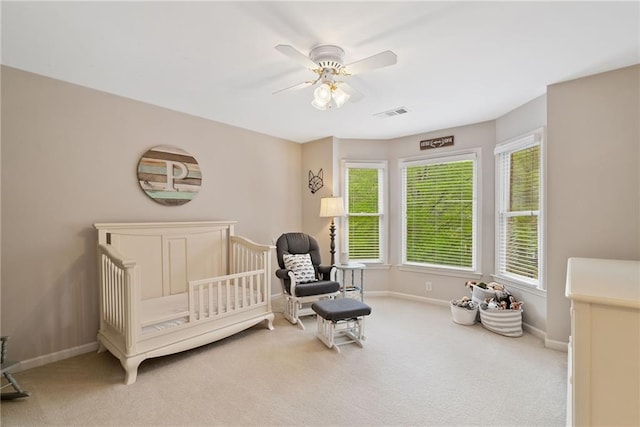 bedroom with ceiling fan, visible vents, a crib, baseboards, and carpet