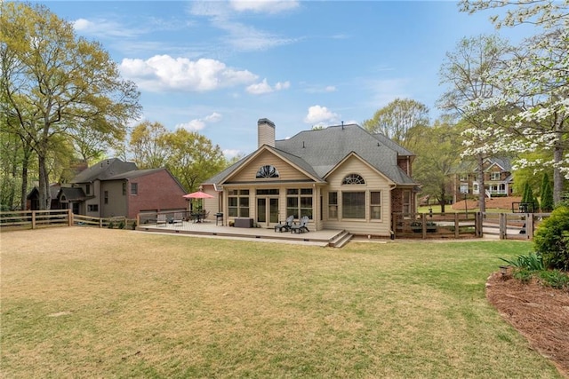 rear view of property featuring a lawn, a fenced backyard, a wooden deck, and a chimney