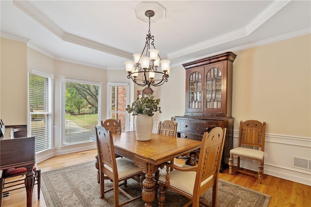 dining space featuring a chandelier, visible vents, ornamental molding, and light wood-style floors