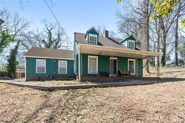 view of front of property featuring covered porch, a chimney, and fence