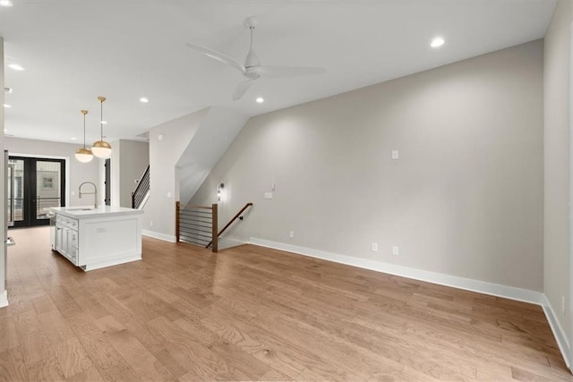 unfurnished living room featuring french doors, light wood-type flooring, ceiling fan, and sink