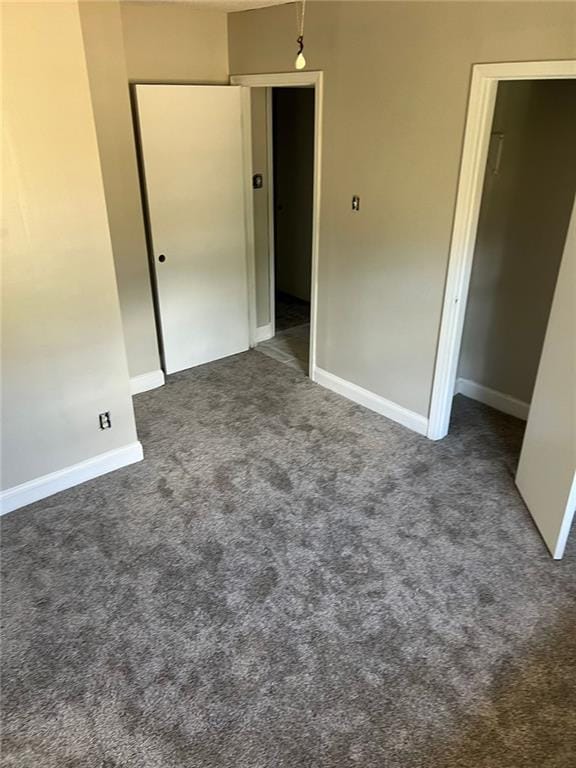 unfurnished bedroom featuring dark colored carpet and a closet