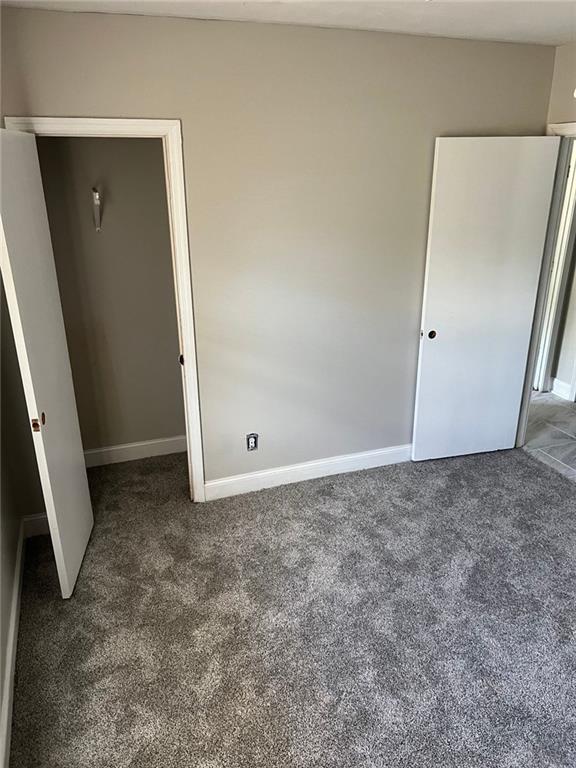 unfurnished bedroom with a closet and dark carpet