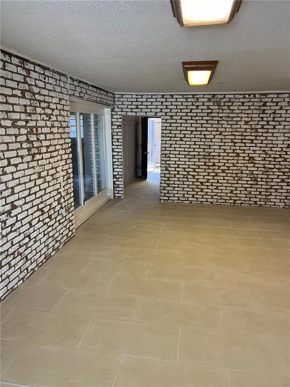 unfurnished room featuring brick wall and a textured ceiling