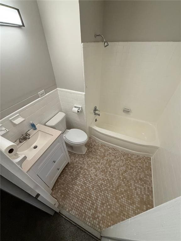 full bathroom with shower / washtub combination, toilet, vanity, tile patterned floors, and tile walls