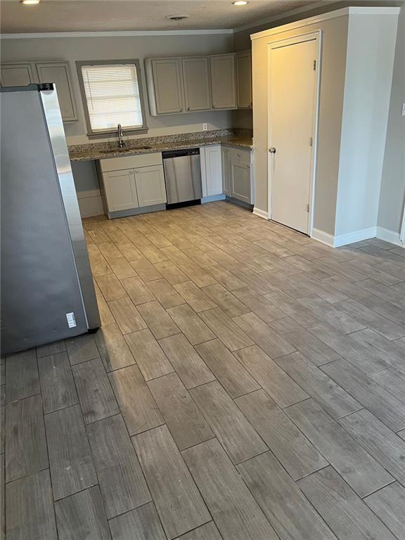 kitchen featuring stainless steel appliances, sink, ornamental molding, and gray cabinets