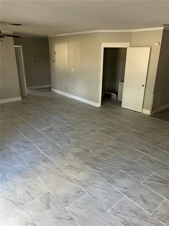 empty room with a textured ceiling, ceiling fan, and ornamental molding