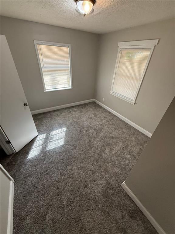 carpeted empty room with a textured ceiling