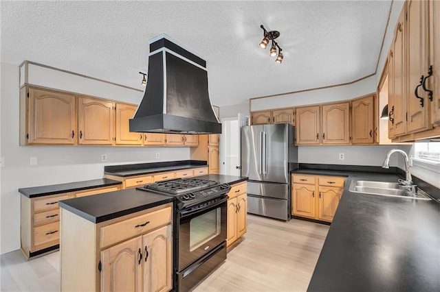 kitchen featuring stainless steel refrigerator, sink, black range with gas cooktop, a kitchen island, and custom exhaust hood