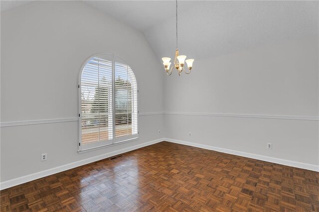 spare room featuring a chandelier, dark parquet flooring, and lofted ceiling