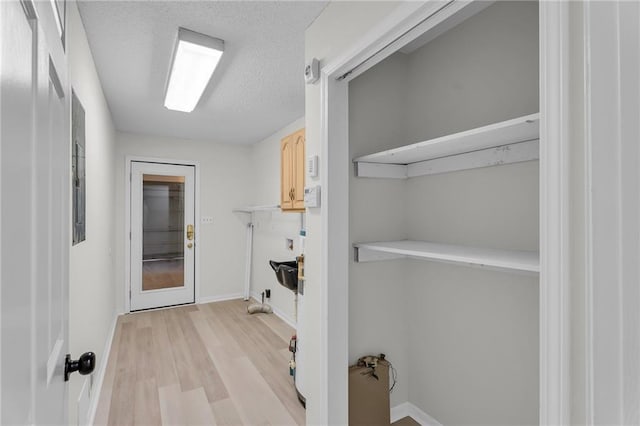 clothes washing area featuring a textured ceiling and light hardwood / wood-style floors