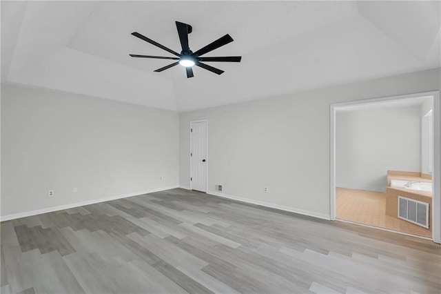 spare room with light hardwood / wood-style flooring, a raised ceiling, and ceiling fan