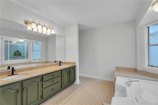 bathroom with tile patterned floors, vanity, a tub to relax in, and a textured ceiling