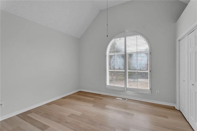 unfurnished bedroom with high vaulted ceiling and light hardwood / wood-style floors