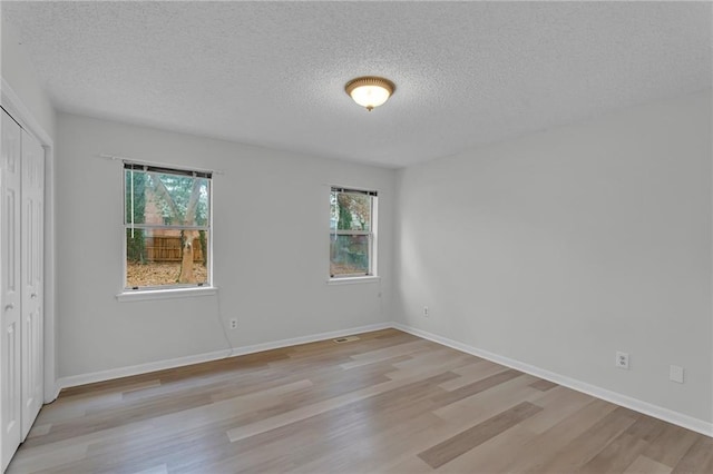 spare room featuring a textured ceiling and light hardwood / wood-style floors