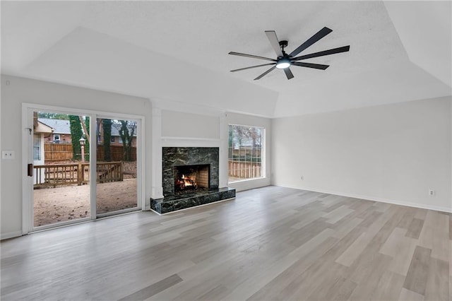 unfurnished living room featuring a fireplace, a tray ceiling, plenty of natural light, and light hardwood / wood-style floors