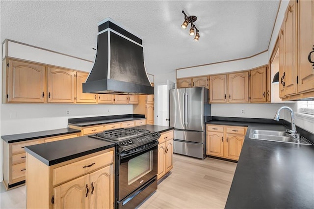 kitchen featuring sink, a center island, black range with gas stovetop, stainless steel fridge, and custom exhaust hood