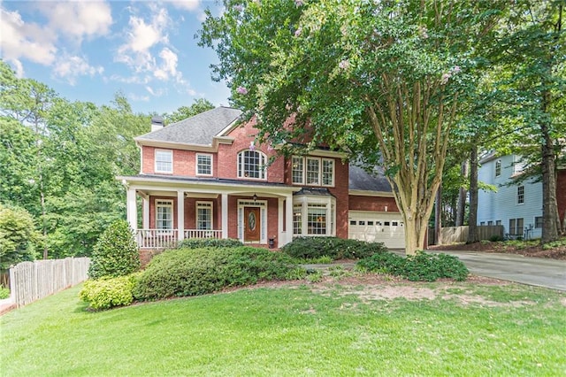 colonial home with a garage, a porch, and a front yard