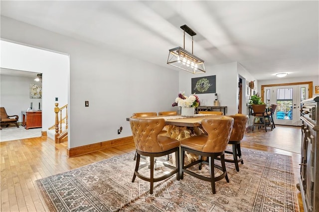 dining area with french doors, baseboards, light wood finished floors, and stairs