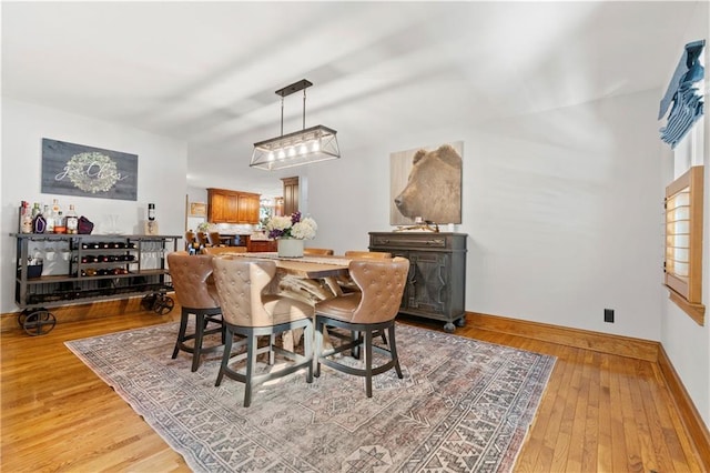 dining space with baseboards and light wood-style floors