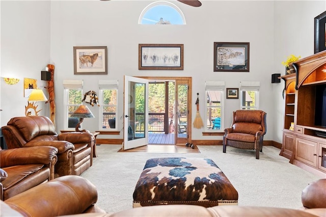 carpeted living room with a high ceiling, baseboards, and a ceiling fan