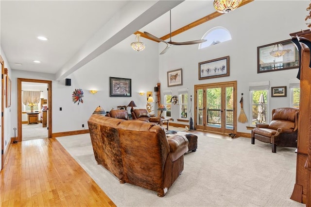 living room featuring light carpet, a high ceiling, baseboards, and beam ceiling