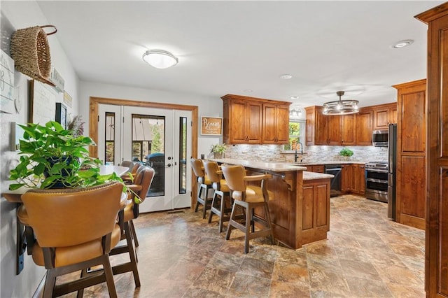 kitchen featuring appliances with stainless steel finishes, a wealth of natural light, backsplash, and a peninsula