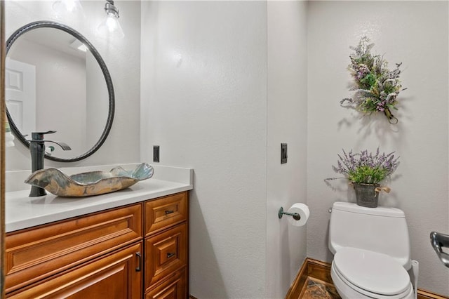 bathroom featuring vanity, toilet, and baseboards