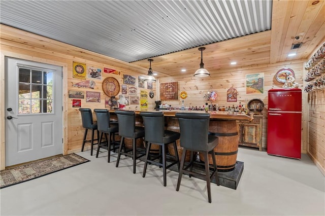 bar with pendant lighting, wooden walls, a dry bar, and finished concrete floors