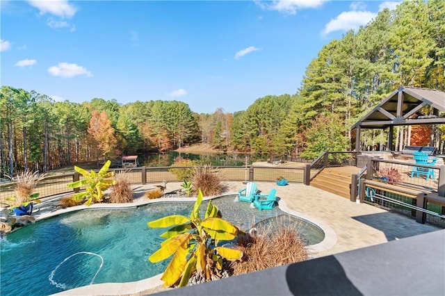 view of swimming pool featuring a wooded view, a patio area, fence, and a fenced in pool