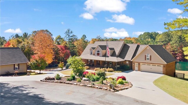 new england style home featuring covered porch, driveway, and a garage