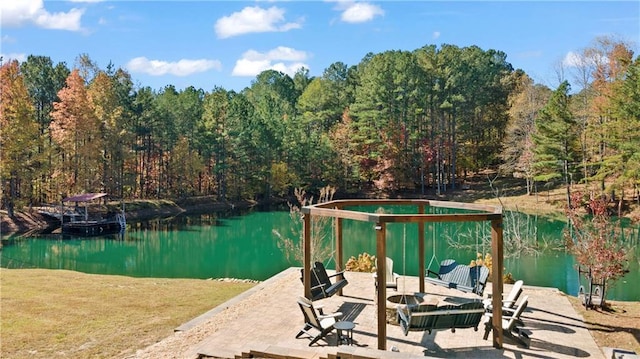 exterior space featuring a water view, a fire pit, and a view of trees