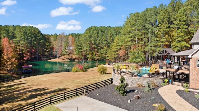 view of patio featuring a water view, fence, and a wooded view