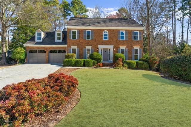 colonial inspired home with a garage, brick siding, driveway, and a front lawn