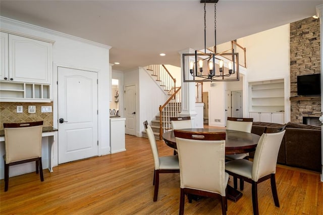 1105 River Laurel Dr, Suwanee, GA 30024 - dining room featuring light wood-type flooring, stairway, a stone fireplace, a chandelier, and recessed lighting