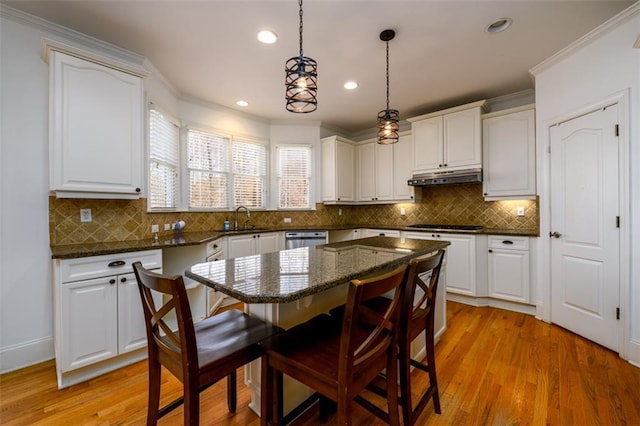 1105 River Laurel Dr, Suwanee, GA 30024 - kitchen featuring under cabinet range hood, a sink, a breakfast bar area, crown molding, and dishwasher