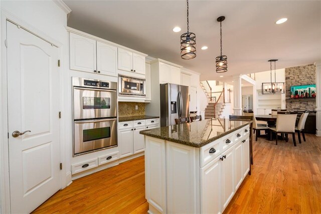 1105 River Laurel Dr, Suwanee, GA 30024 - kitchen with appliances with stainless steel finishes, light wood-style flooring, white cabinetry, a kitchen island, and decorative light fixtures