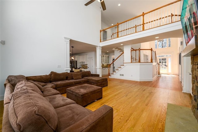 1105 River Laurel Dr, Suwanee, GA 30024 - living room with ornate columns, a towering ceiling, a ceiling fan, light wood-type flooring, and baseboards