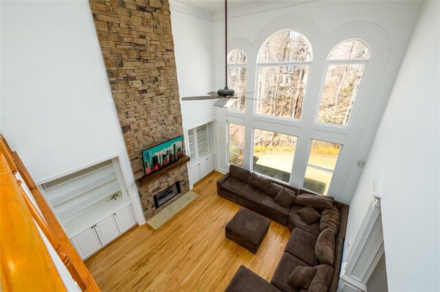 1105 River Laurel Dr, Suwanee, GA 30024 - living area with light wood finished floors, a stone fireplace, ceiling fan, ornamental molding, and a high ceiling