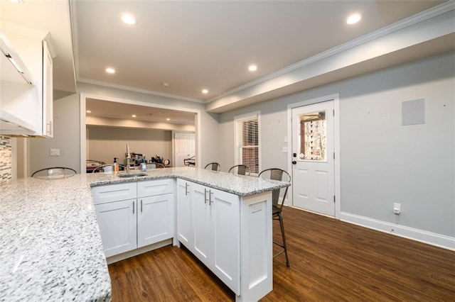 1105 River Laurel Dr, Suwanee, GA 30024 - kitchen featuring a kitchen bar, dark wood-type flooring, crown molding, white cabinets, and a peninsula