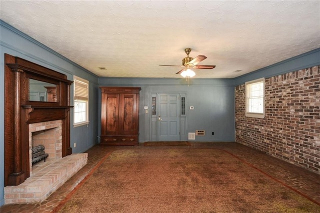 unfurnished living room featuring a textured ceiling, a brick fireplace, ceiling fan, and carpet flooring