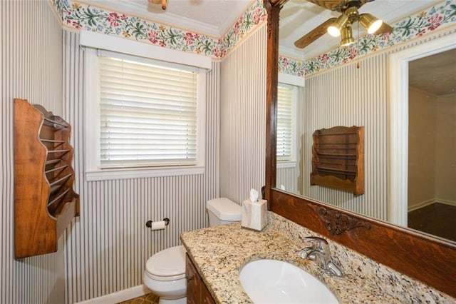 half bathroom featuring wallpapered walls, toilet, vanity, and ceiling fan