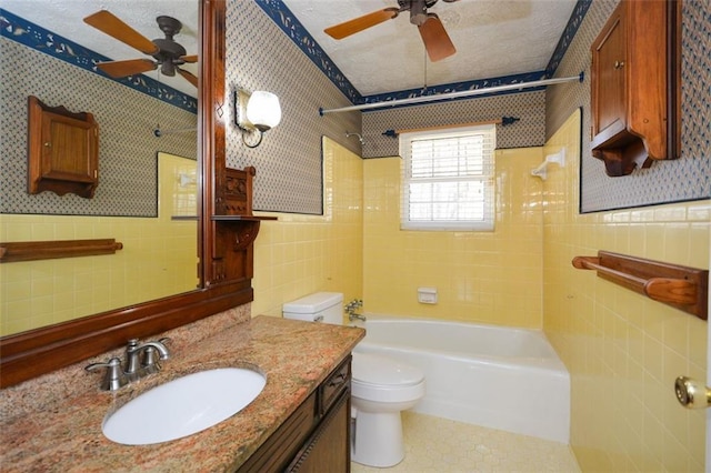 bathroom featuring a textured ceiling, tile walls, and wallpapered walls