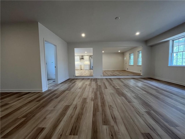 unfurnished living room featuring recessed lighting, wood finished floors, and baseboards