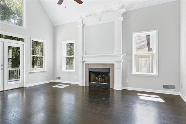 unfurnished living room featuring ceiling fan, dark hardwood / wood-style flooring, high vaulted ceiling, a tiled fireplace, and ornamental molding