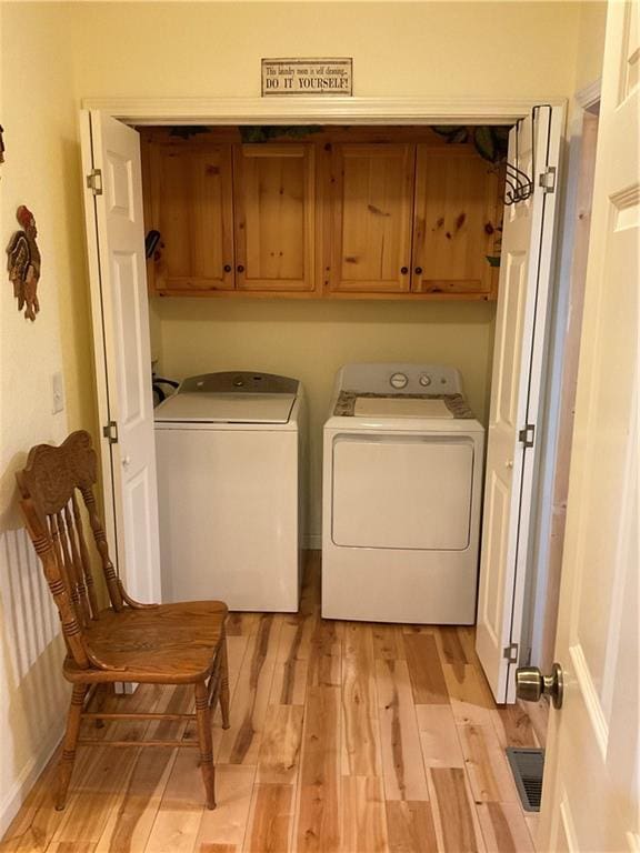 laundry room with light wood-style flooring, cabinet space, baseboards, and washer and clothes dryer