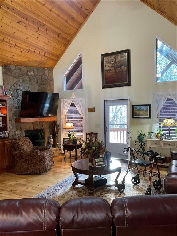 living area featuring wooden ceiling, wood finished floors, a fireplace, and high vaulted ceiling