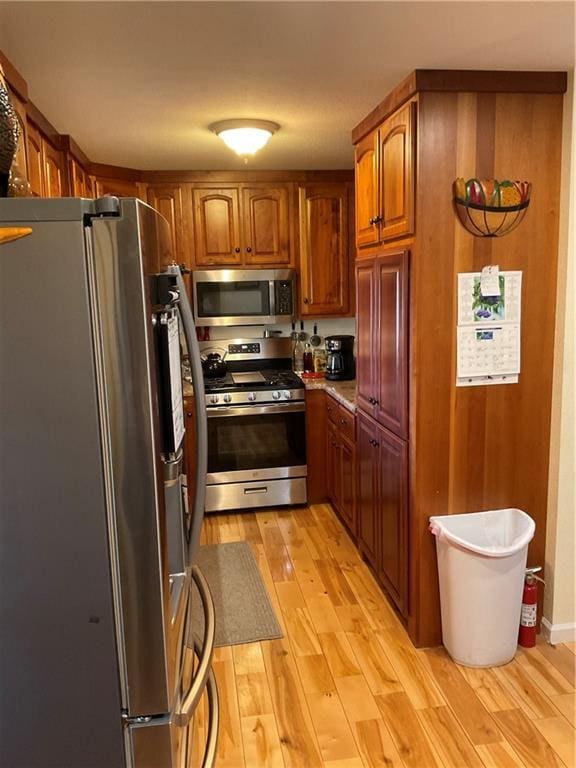 kitchen with brown cabinets, stainless steel appliances, and light wood-style floors